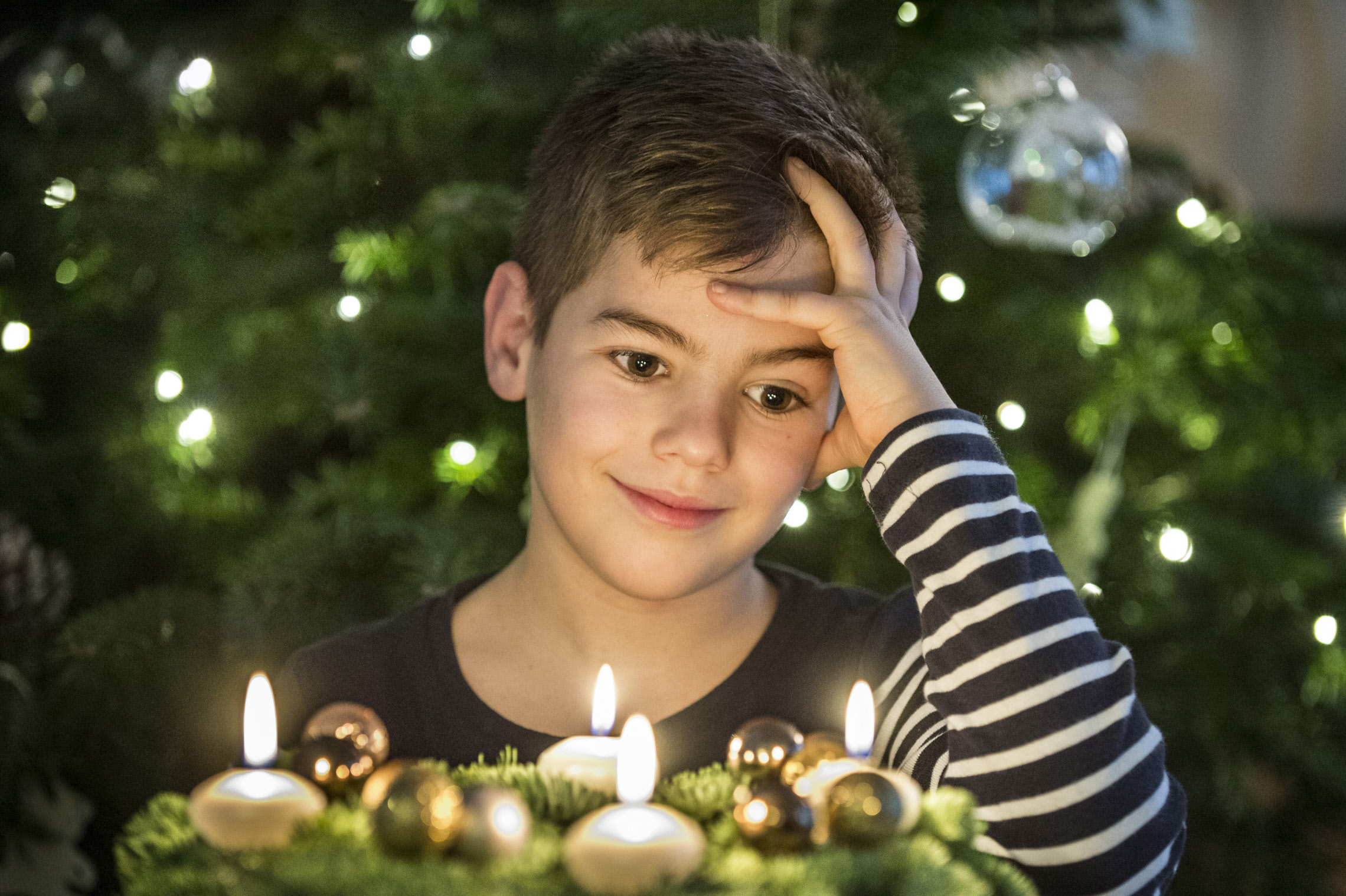 Petit garçon devant une couronne de l'Avent et ses bougies allumées